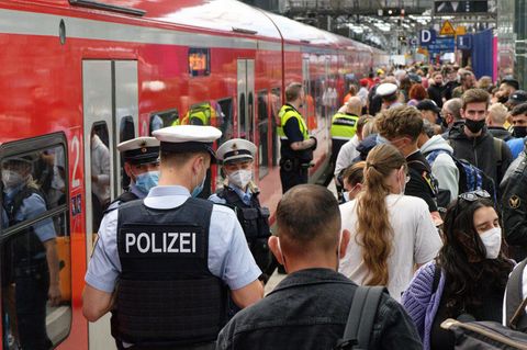 Polizei und Mitarbeiter der Deutschen Bahn weisen Reisenden auf einem überfülltem Bahnsteig im Hauptbahnhof den Weg