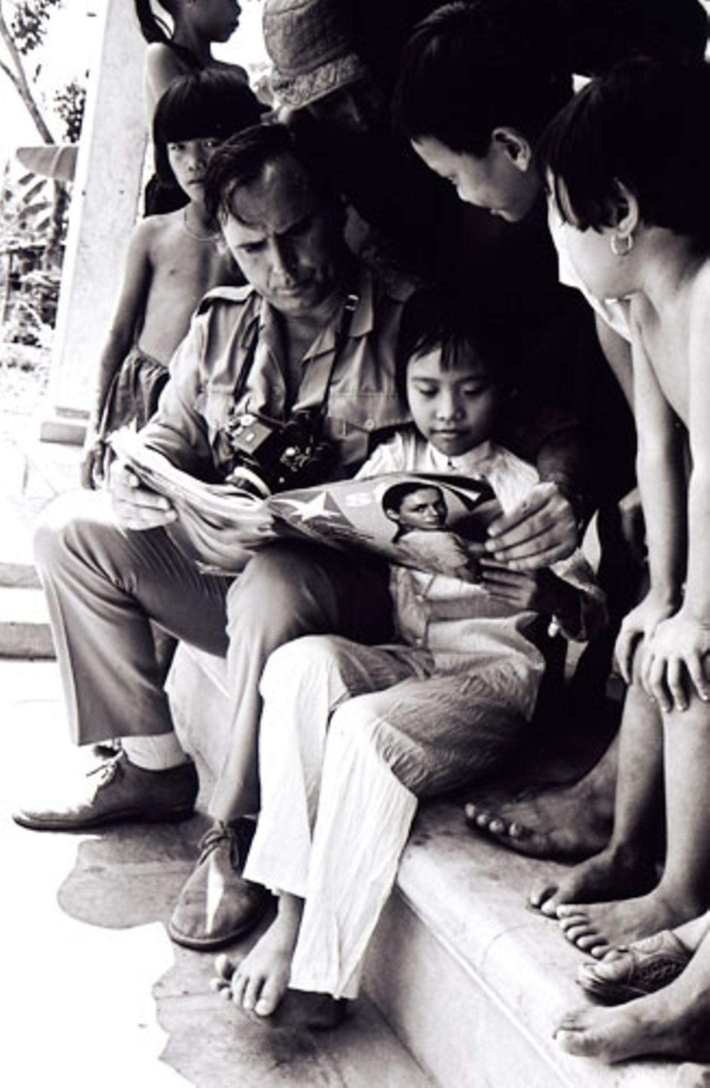 stern-Fotograf Perry Kretz bei seinem ersten Besuch 1973. Staunend betrachten Kim Phuc und ihre Spielkameraden eine Ausgabe des stern.