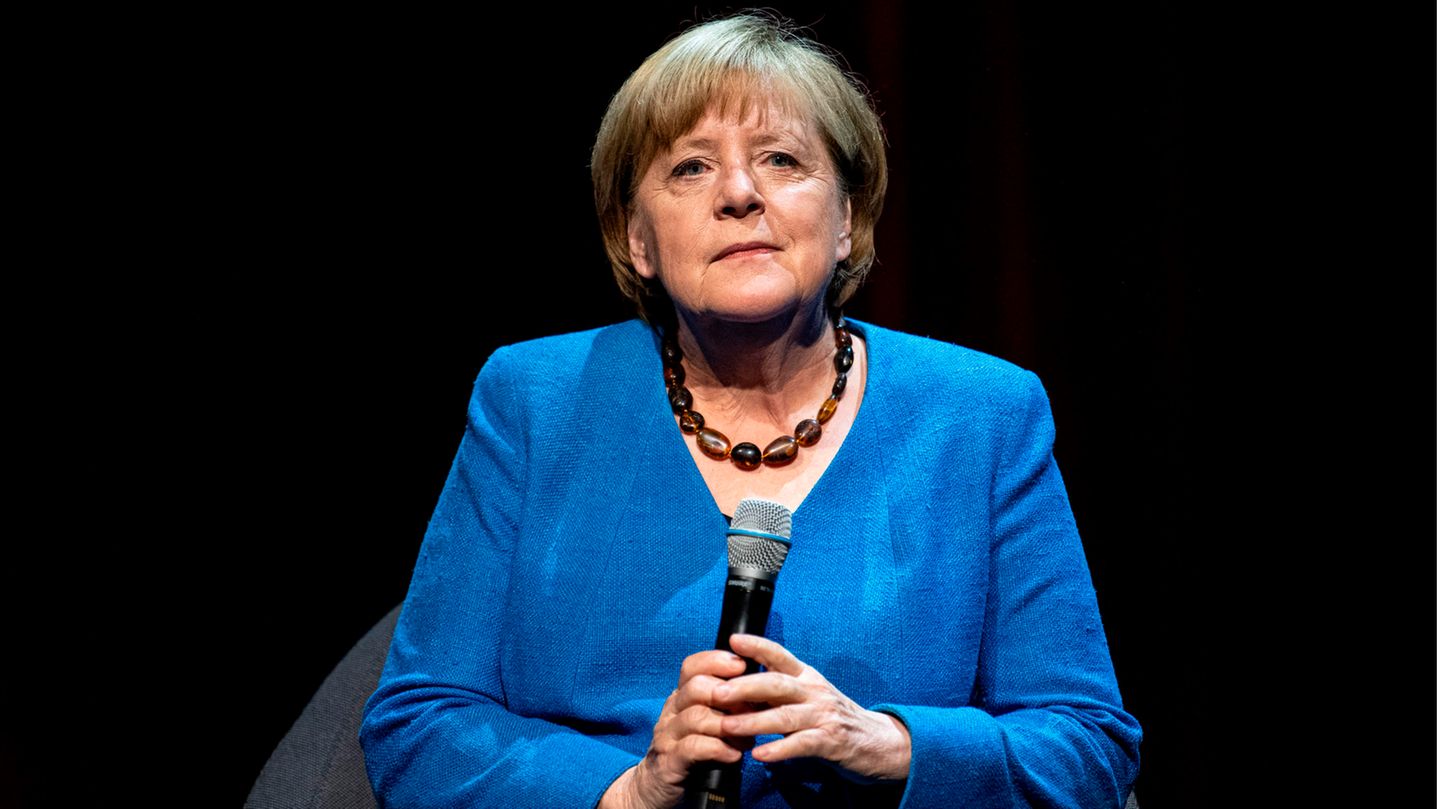 Angela Merkel im blauen Jacket mit Mikro in der Hand