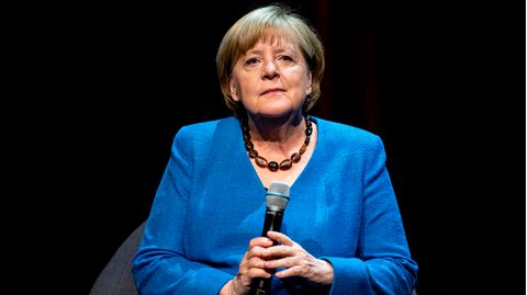 Angela Merkel im blauen Jacket mit Mikro in der Hand