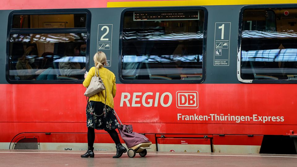Eine Frau geht an einem Regionalexpress auf dem Hauptbahnhof Leipzig entlang