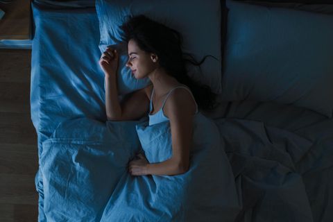 Eine Frau schläft entspannt in ihrem Bett