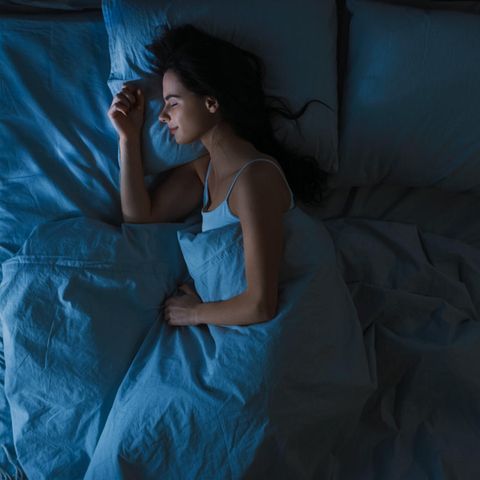 Eine Frau schläft entspannt in ihrem Bett