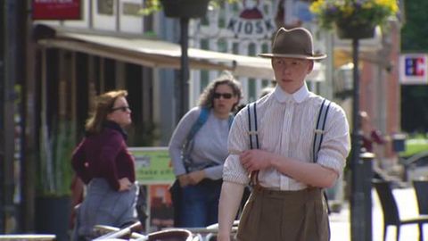Ein junger Mann läuft auf der Straße in alter Mode gekleidet