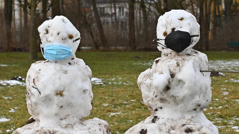 Zwei Schneefiguren mit Coronavirus-Schutzmasken