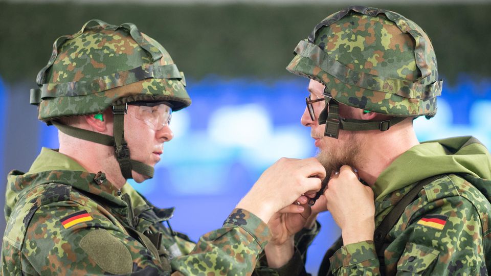 Ein Jäger der Bundeswehr hilft einem Reservisten beim Schließen des Helms