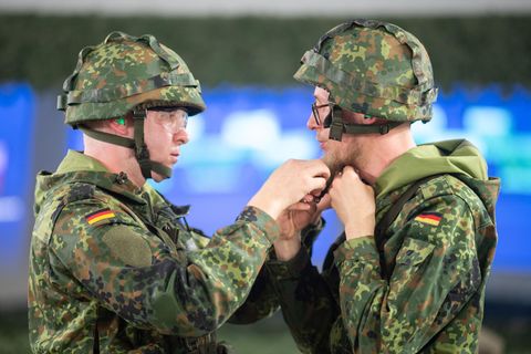 Ein Jäger der Bundeswehr hilft einem Reservisten beim Schließen des Helms