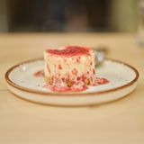 Kretischer Cheesecake – Kritikó tsiskéik      Zutaten:  Für den Boden  300 g Paximádi (kretischer Gerstenzwieback), 150 g Butter, 100 g Zucker, 1Ei  Für die Füllung  1 kg Mizíthra-Käse, gut abgetropft ,160 g Puderzucker, Mark von 1 Vanilleschote (oder 2 TL Vanilleextrakt), 100 g griechischer Joghurt, Abrieb von 1 unbehandelten Zitrone, 4 Eier      Zubereitung:      Für den Boden das Paximádi zerbröseln. Die Butter in einem Topf bei mittlerer Hitze zerlassen und über den Gerstenzwieback gießen. Zucker und Ei zugeben und alles gut vermengen. Den Boden einer Springform (Durchmesser 24 cm) mit Backpapier auslegen und den Rand fetten. Die Mischung auf dem Springformboden verteilen und mit einem Löffel gut festdrücken.  Den Backofen auf 170 °C Ober-/Unterhitze vorheizen.  Für die Füllung Mizíthra-Käse, Zucker und Vanillemark in einer Schüssel mit dem Handrührgerät auf niedriger Stufe cremig schlagen. Joghurt und Zitronenabrieb unter die Masse rühren. Zum Schluss die Eier verquirlen und unterheben.  Die Mizíthra-Mischung auf den Kuchenboden geben und glatt streichen. Die Form (vorsichtig) ein paarmal auf die Arbeitsfläche klopfen, damit eventuelle Luftbläschen verschwinden. Den Cheesecake im Backofen in etwa 1 Stunde goldbraun backen.  Den Cheesecake abkühlen lassen und nach Belieben pur oder mit Toppings servieren.