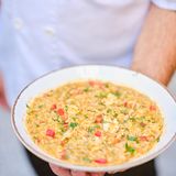 Orzo-Pasta mit Garnelen – Kritharóto me garídes      Zutaten:  1 Stange Lauch, 1 rote Spitzpaprika, 1 Zwiebel, 1 Knoblauchzehe, 4 EL Olivenöl, 50 g Butter, 500 g küchenfertige Garnelen, 500 g Orzo-Pasta, 1,5 l heißer Fischfond, 100 ml Weißwein, 400 g geriebene Tomaten, Salz, frisch gemahlener schwarzer Pfeffer  Zum Servieren  2 EL gehackte Petersilie      Zubereitung:      Den Lauch in dünne Ringe schneiden. Die Paprika würfeln. Zwiebel und Knoblauch fein hacken.  Olivenöl und Butter in einer tiefen Pfanne erhitzen. Zwiebel, Knoblauch, Lauch und Paprika hineingeben und etwas braten. Die Garnelen etwa 2 Minuten mitbraten, dann aus der Pfanne nehmen und warm beiseitestellen.  Anschließend die Orzo-Pasta hinzugeben, die Temperatur erhöhen und alles umrühren. Etwas Fischfond angießen und warten, bis die Nudeln die Flüssigkeit aufgenommen haben. Alles mit dem Weiß- wein ablöschen und die geriebenen Tomaten dazugeben.  Unter ständigem Rühren den restlichen Fischfond nach und nach hinzufügen. Wenn die Nudeln nach etwa 15 Minuten gar sind, die Garnelen unterrühren.  Die Pasta mit Salz und Pfeffer würzen, in tiefen Tellern anrichten, mit Petersilie garnieren und servieren.