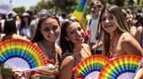 Drei Frauen mit Regenbogen-Fächern