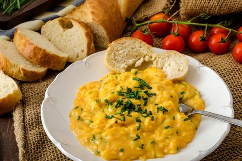 Frisches Rührei nach französischer Art mit Schnittlauch mit französischem Baquette und Mini-Tomaten