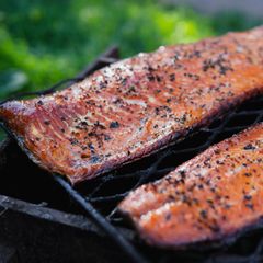 Heiße geräucherte Lachsfilets mit Sesamsamen, Papier und Gewürzen auf schwarzem Gitter