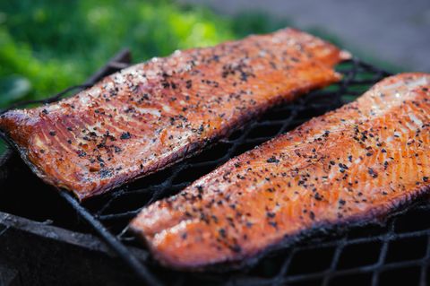 Heiße geräucherte Lachsfilets mit Sesamsamen, Papier und Gewürzen auf schwarzem Gitter