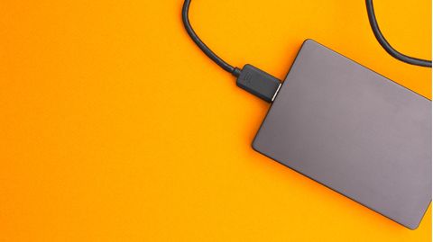 Externe Festplatte für PS5: Ein externer SSD-Speicher liegt auf einem gelben Hintergrund.