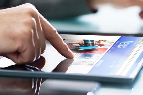 Eine Hand scrollt auf dem Tablet auf einer Nachrichten-Seite