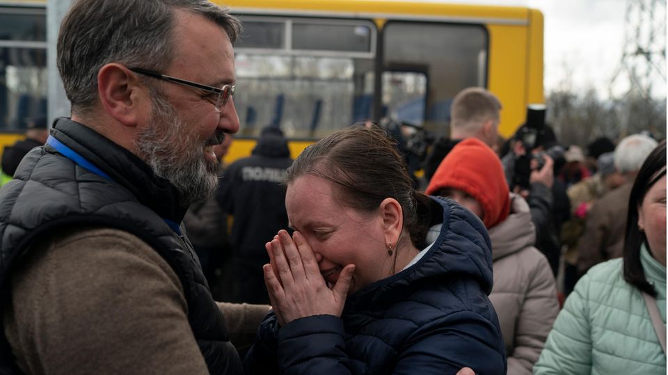 Eine Frau steht einem Mann gegenüber und wischt sich Tränen aus dem Gesicht