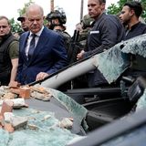 Scholz begutachtet ein stark beschädigtes Auto in Irpin. 