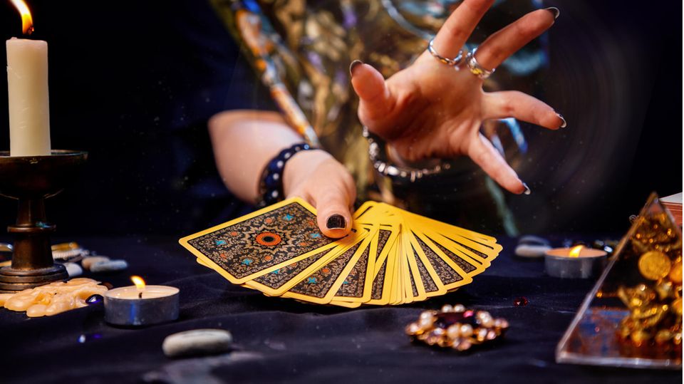 Eine Frau hält einen Stapel Tarotkarten in Ihrer Hand.