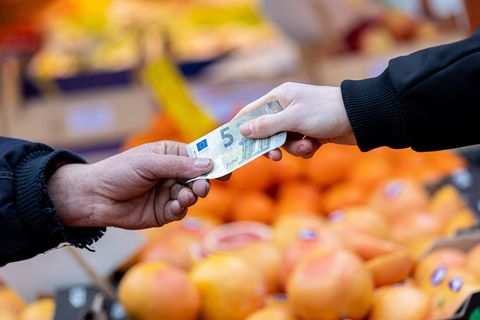 Inflation: Eine Hand übergibt einen 5-Euro-Schein an jemanden