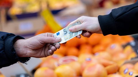 Inflation: Eine Hand übergibt einen 5-Euro-Schein an jemanden
