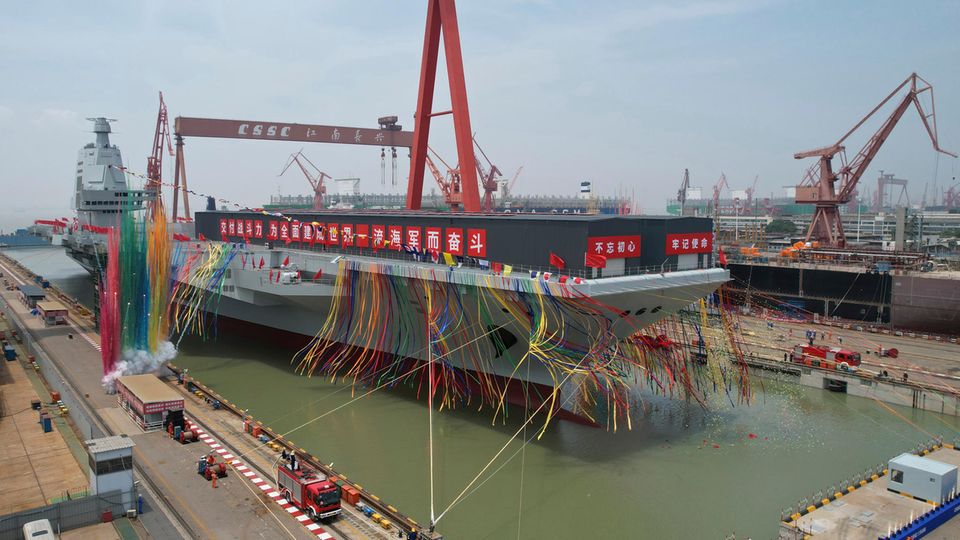 Ein Flugzeugträger ist feierlich geschmückt und legt an einem Hafen