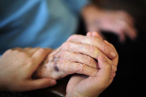 Die Hand einer Pflegefachkraft liegt auf der Hand einer Bewohnerin des Seniorenheims