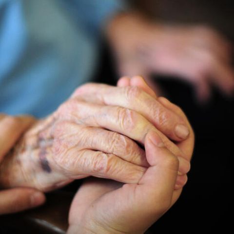 Die Hand einer Pflegefachkraft liegt auf der Hand einer Bewohnerin des Seniorenheims