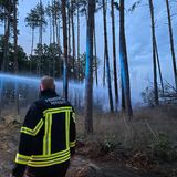 Ein Feuerwehrmann steht bei Löscharbeiten auf einem Weg