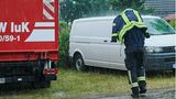 Ein Feuerwehrmann schützt sich mit seiner Einsatzjacke vor dem starken Regen, während er auf dem Bereitstellungsraum von Feuerwehr, THW und Polizei nahe Treuenbrietzen läuft.   Zunächst brannten nachts noch 135 Hektar Waldflächen bei Treuenbrietzen – 80 Kilometer südwestlich von Berlin, wie Behördenvertreter vor Ort berichteten. Kurz nach 7 Uhr wurde der Regen aber immer kräftiger.