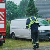 Ein Feuerwehrmann schützt sich mit seiner Einsatzjacke vor dem starken Regen, während er auf dem Bereitstellungsraum von Feuerwehr, THW und Polizei nahe Treuenbrietzen läuft.   Zunächst brannten nachts noch 135 Hektar Waldflächen bei Treuenbrietzen – 80 Kilometer südwestlich von Berlin, wie Behördenvertreter vor Ort berichteten. Kurz nach 7 Uhr wurde der Regen aber immer kräftiger.