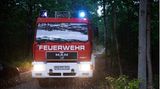 Im Scheinwerferlicht eines Feuerwehrfahrzeugs ist der strömende Regen zu sehen, der Montagmorgen in einem Waldstück zwischen Treuenbriezen und Beelitz fällt