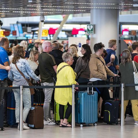 Reisende stehen in der Abflughalle des Flughafens Schiphol Schlange