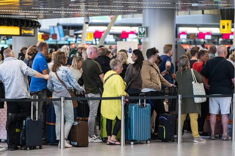 Reisende stehen in der Abflughalle des Flughafens Schiphol Schlange