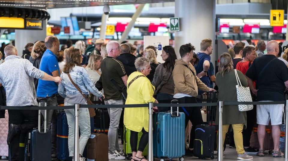 Travelers are queuing in the departure hall of Schiphol Airport