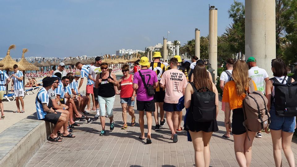 Touristen mit Motto-Shirts an der Playa de Palma auf Mallorca
