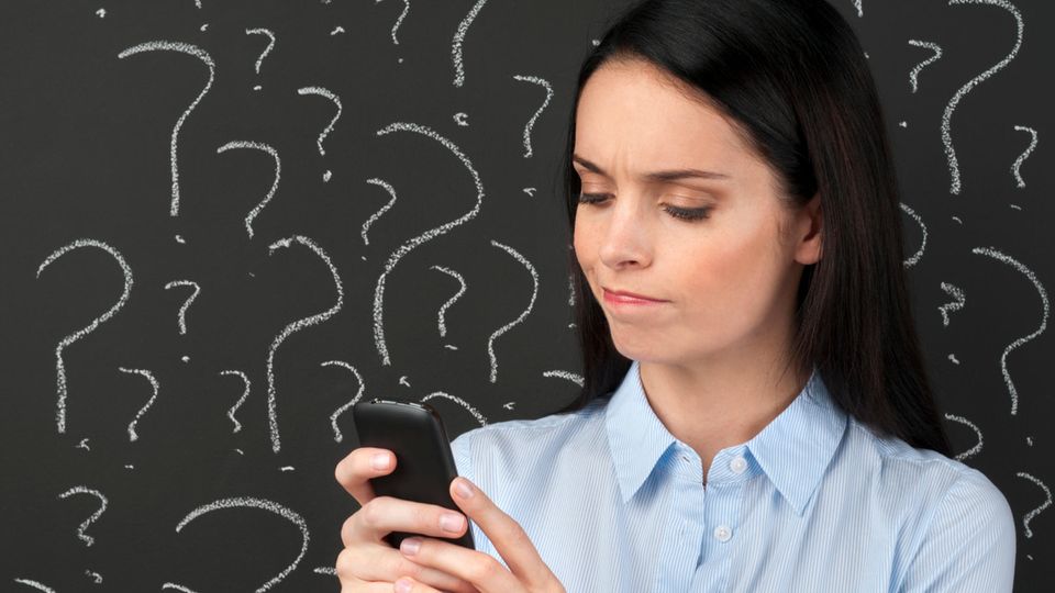 Eine junge Frau schaut verwirrt auf ihr Smartphone