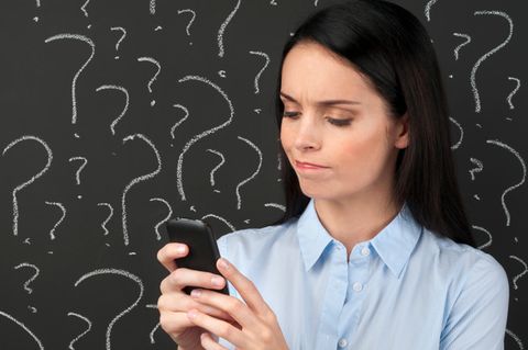 Eine junge Frau schaut verwirrt auf ihr Smartphone