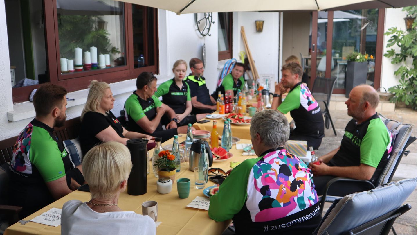 Osnabruck Men and women in cycling gear sit around a table under an umbrella