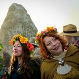 Frauen mit Blumenkränzen auf dem Kopf stehen vor Stonehenge