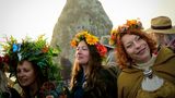 Frauen mit Blumenkränzen auf dem Kopf stehen vor Stonehenge