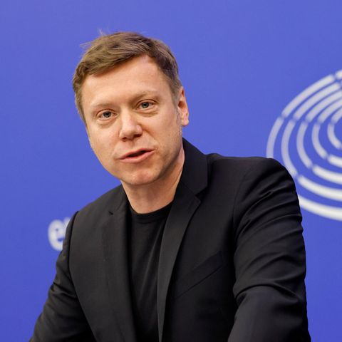 Martin Schirdewan vor einer blauen Wand mit dem Logo des EU-Parlaments