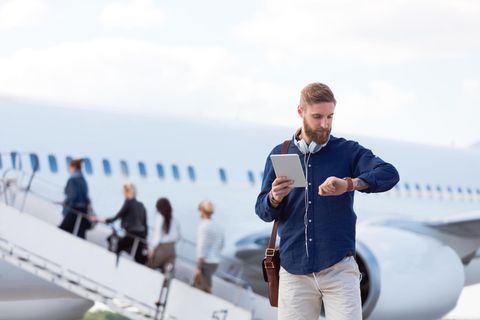 EIn Mann schaut vor dem Flug auf seine Uhr