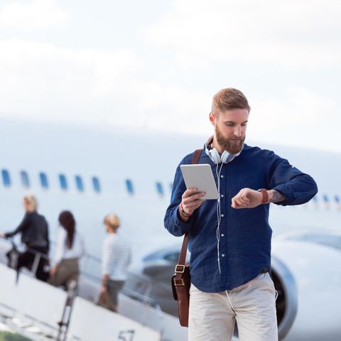 EIn Mann schaut vor dem Flug auf seine Uhr
