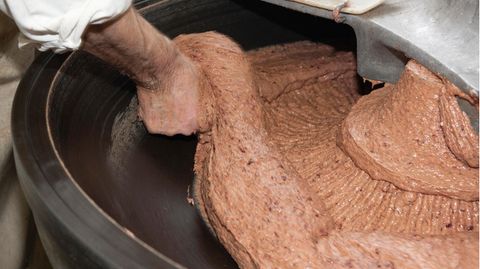 Separatorenfleisch: Ein Metzger greift in einen mit Hackfleisch gefüllten Kutter