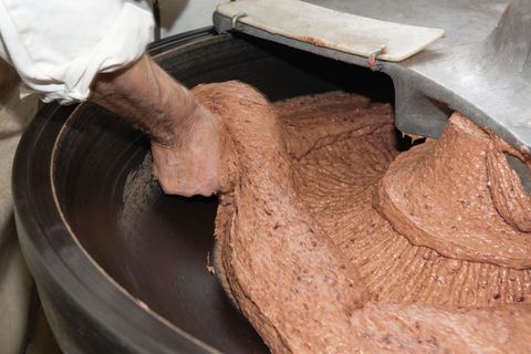 Separatorenfleisch: Ein Metzger greift in einen mit Hackfleisch gefüllten Kutter