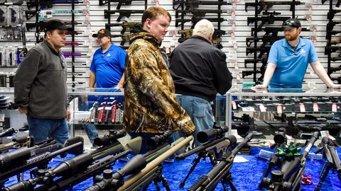Kunden in einem Waffengeschäft betrachten am Black Friday ausgestellte Waffen und lassen sich beraten