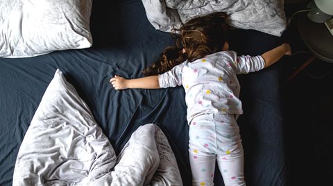 Süßes kleines vierjähriges Mädchen, das auf dem Bett ihrer Eltern schläft