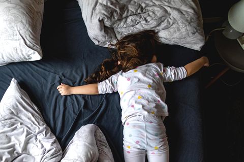 Süßes kleines vierjähriges Mädchen, das auf dem Bett ihrer Eltern schläft