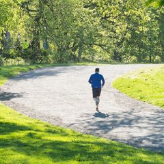 Ein Mann joggt durch eine Baumallee