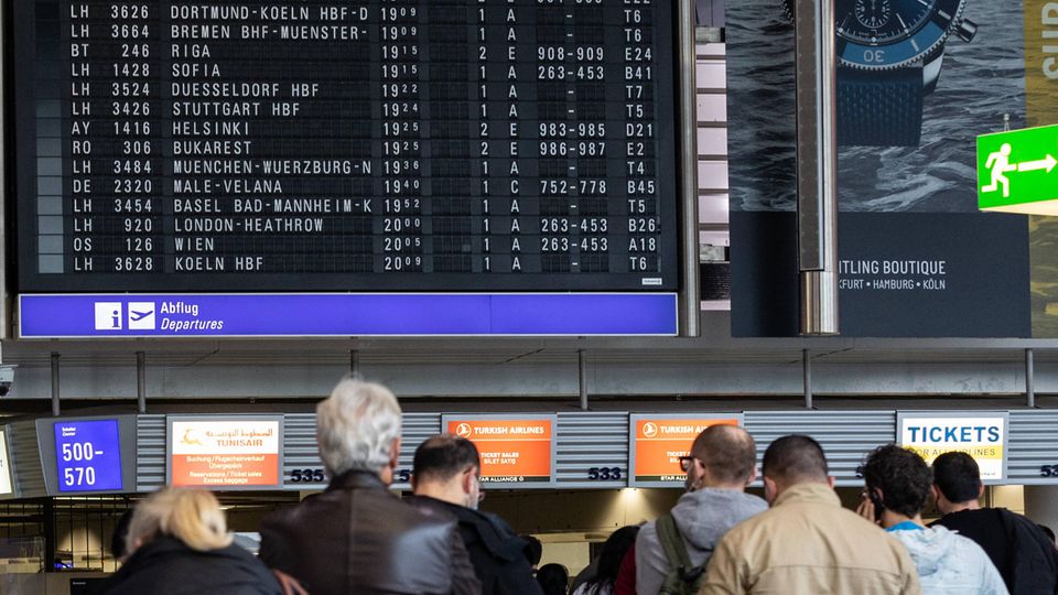 Flughafen-Passagiere vor der Anzeige mit Flügen in Frankfurt